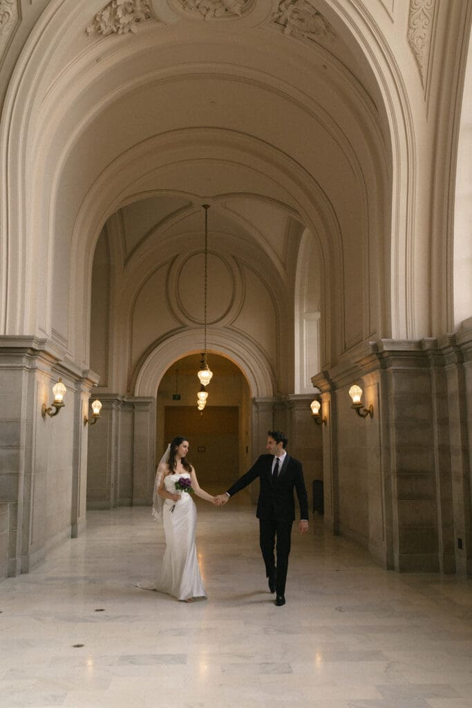 Bride and groom walking down the 4th floor hallway in San Francisco City Hall