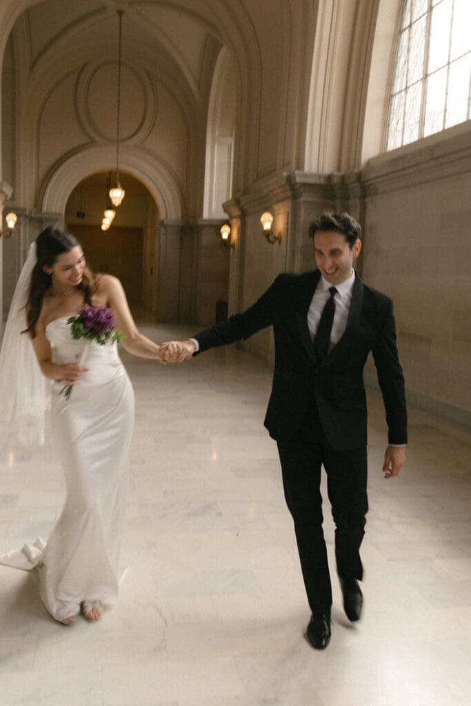 Blurry photo of bride and groom walking down the 4th floor hallway in San Francisco City Hall