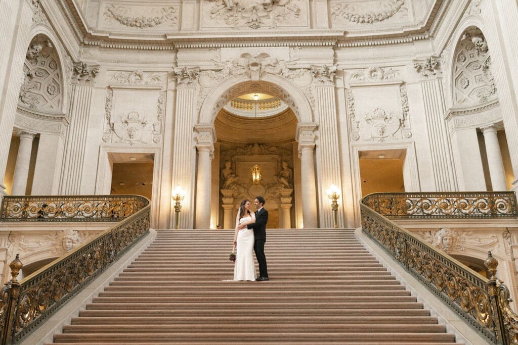 Bride and groom portrait inside San Francisco City Hall on grand staircase