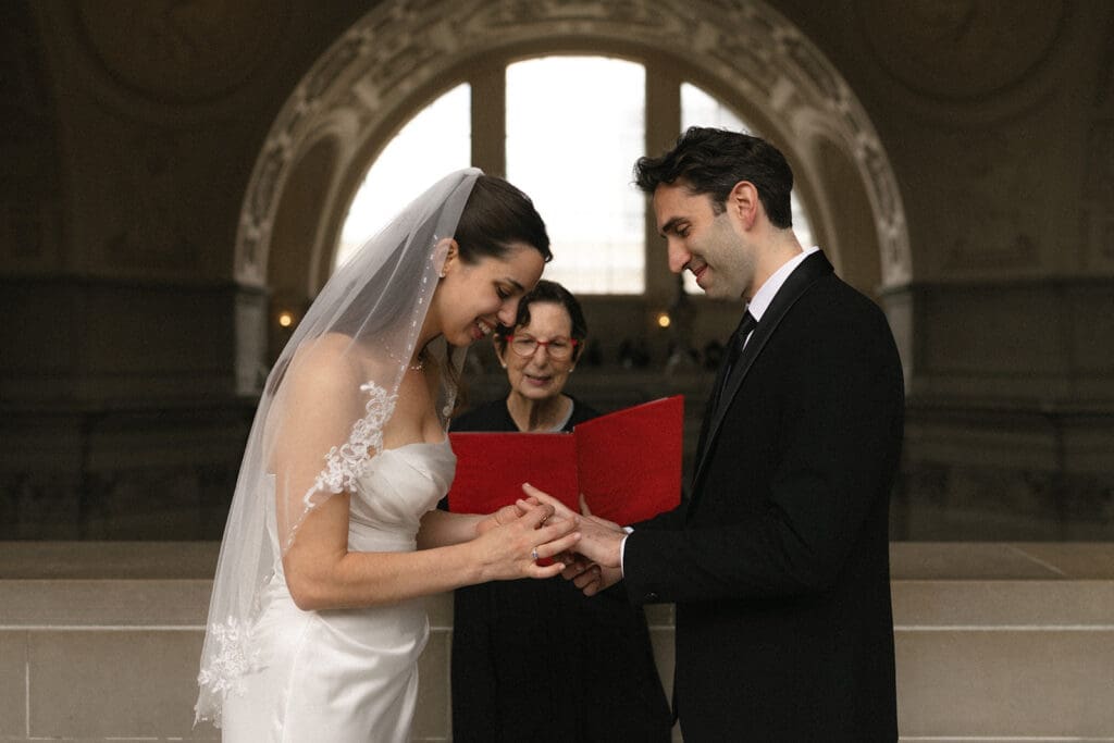 Bride and groom exchanging rings during San Francisco City Hall wedding ceremony