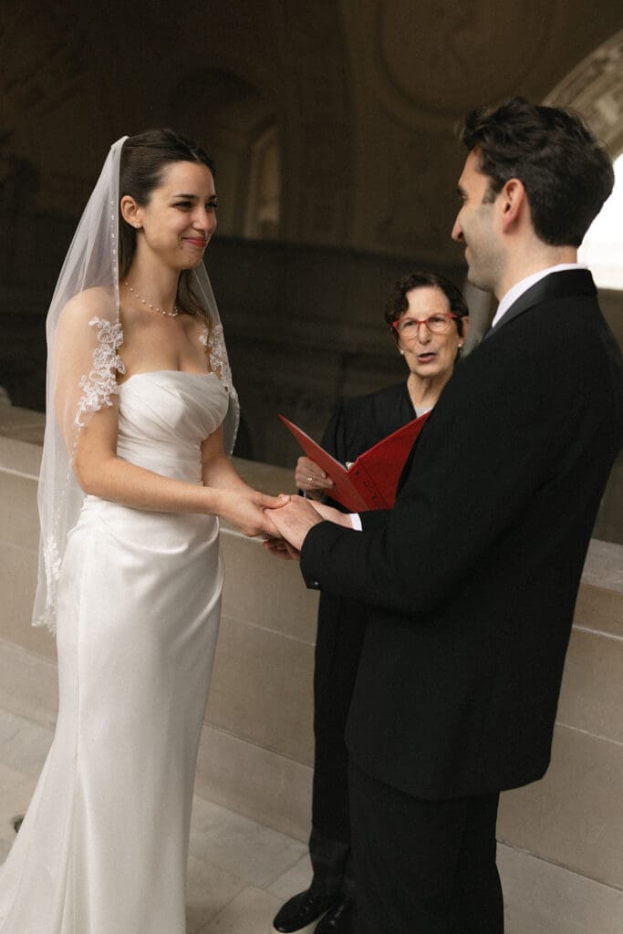 Bride and groom exchanging rings during San Francisco City Hall wedding ceremony