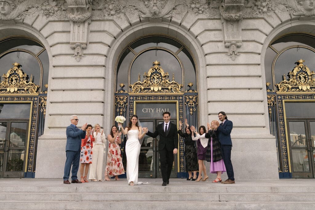 Bride and groom exit San Francisco City hall to cheering guests 