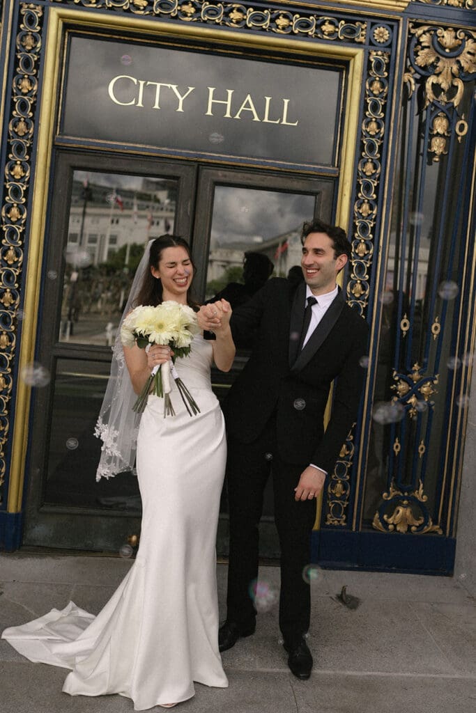 Bride and groom exit San Francisco City hall with bubbles