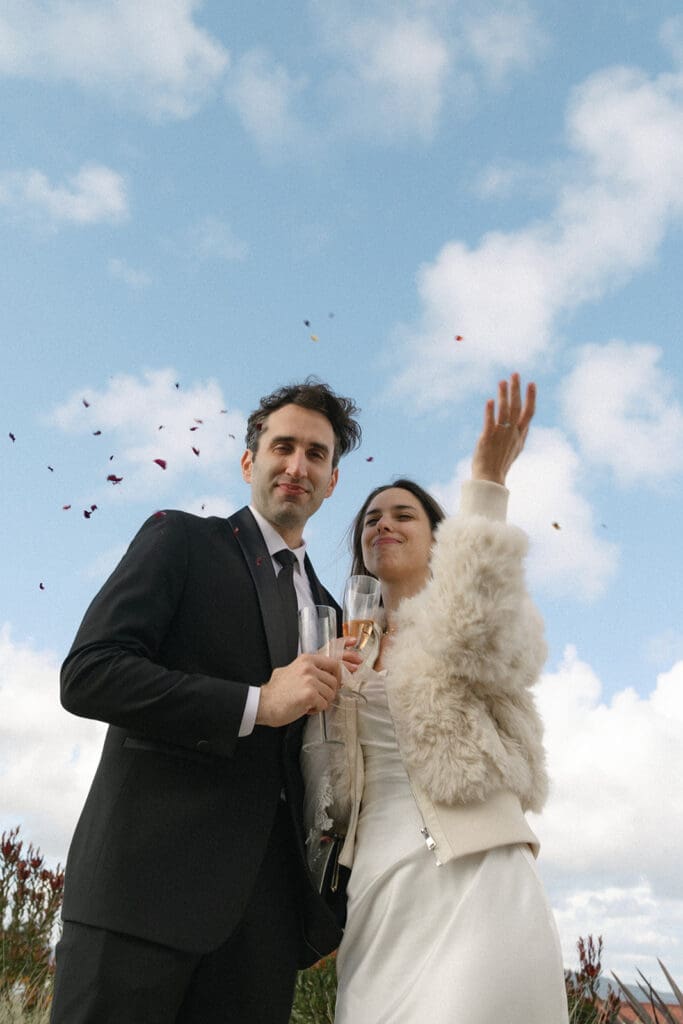 Bride and groom throw celebratory flower petals in the air