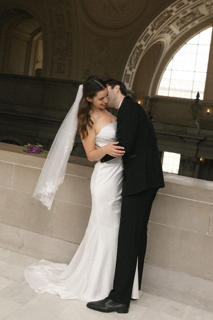 Photo of bride and groom touching foreheads and laughing at San Francisco City Hall