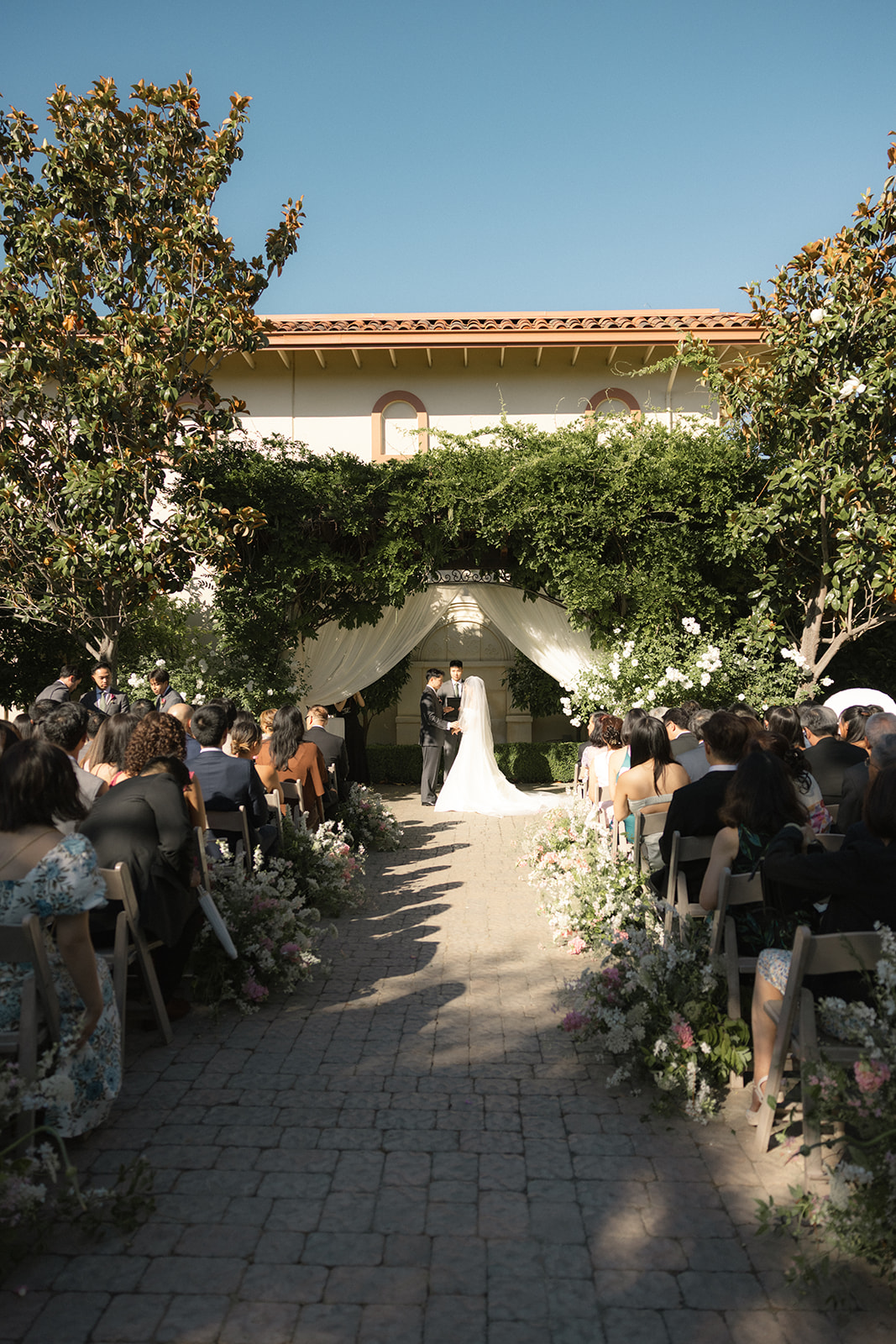 Outdoor wedding ceremony beneath a vine-covered arbor at casa real at ruby hill winery, showcasing one of the most beautiful bay area wedding venues.