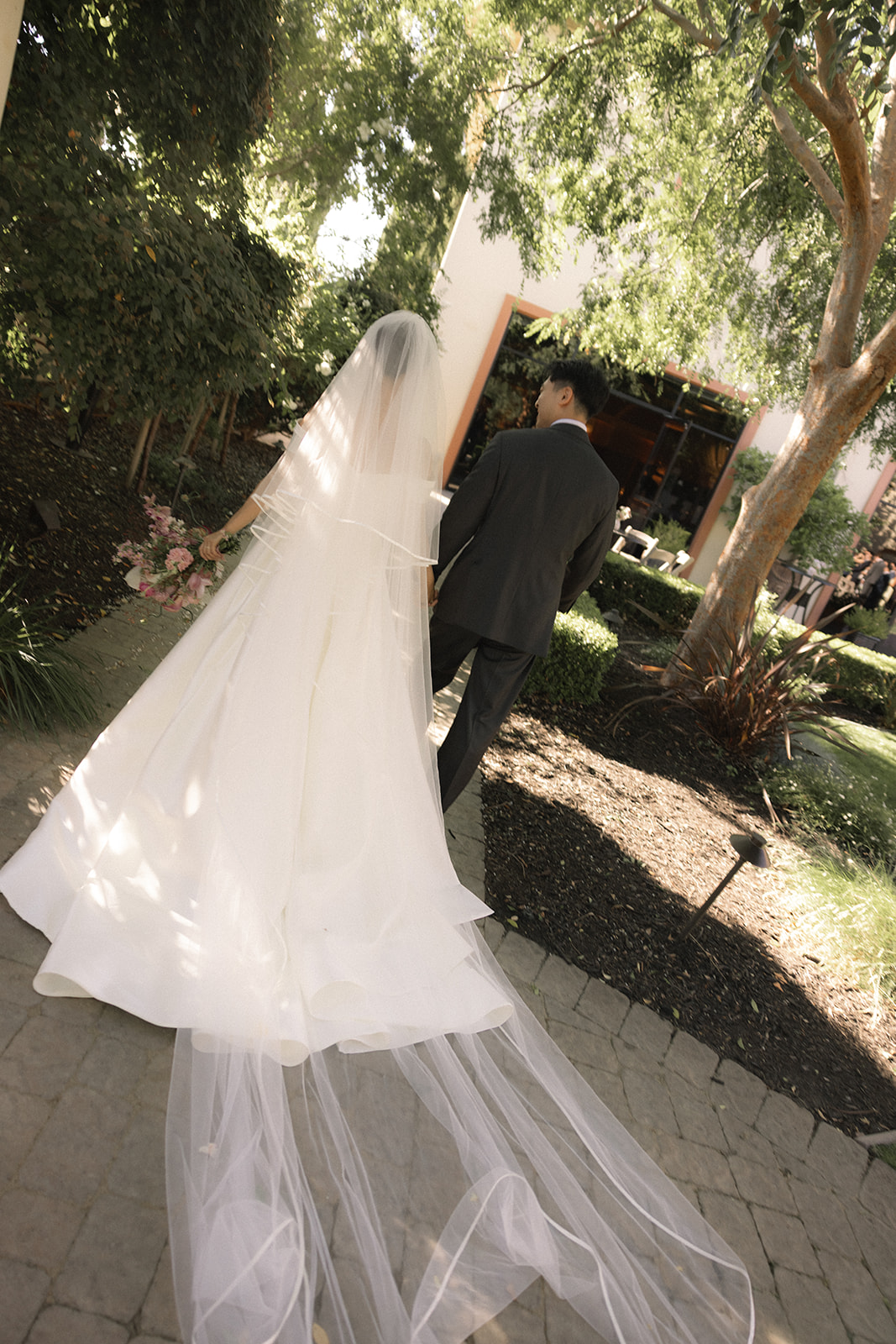 Newlyweds walking through the garden paths at casa real at ruby hill winery, highlighting one of the most scenic bay area wedding venues.