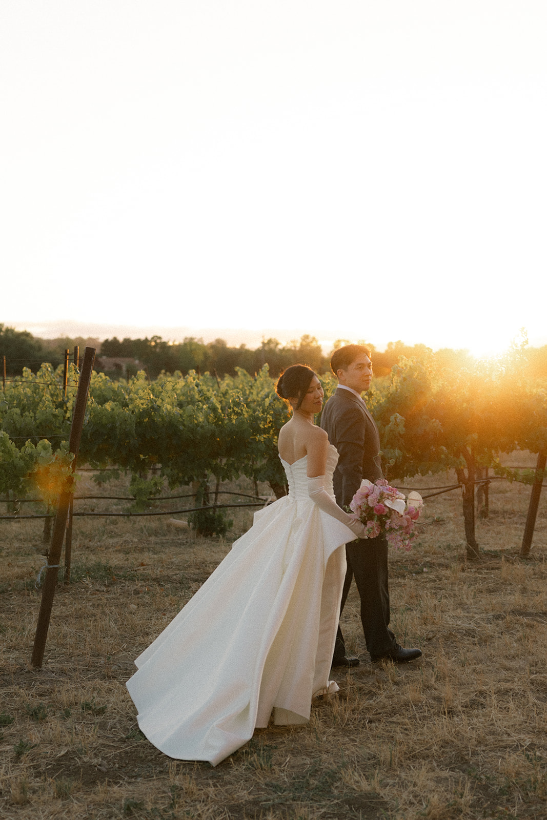 Bride and groom posing back-to-back in the vineyard during golden hour at casa real at ruby hill winery, featured in romantic casa real at ruby hill winery photos.