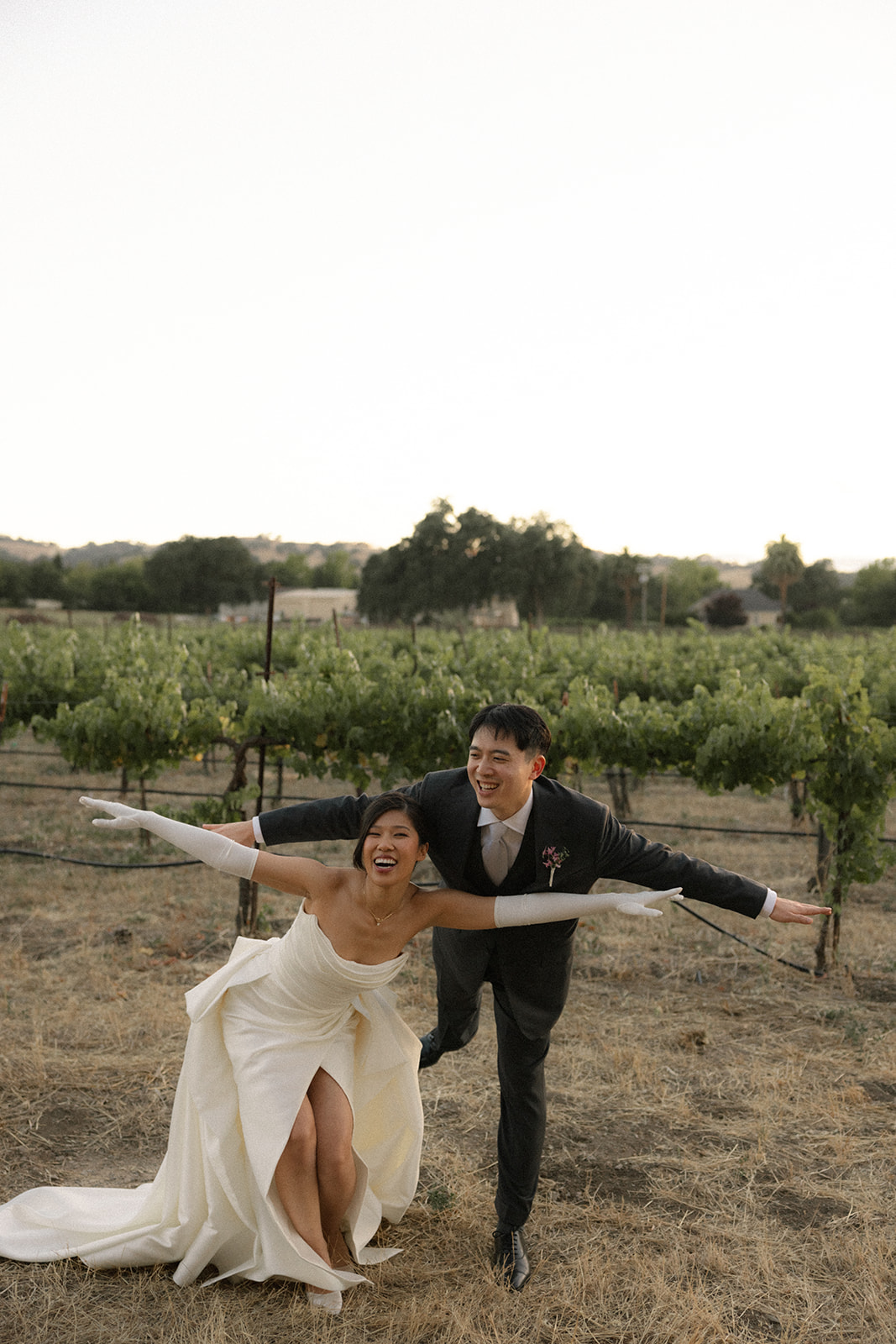 Bride and groom embracing beneath a white parasol in the vineyard at casa real at ruby hill winery, photographed by a bay area wedding photographer.