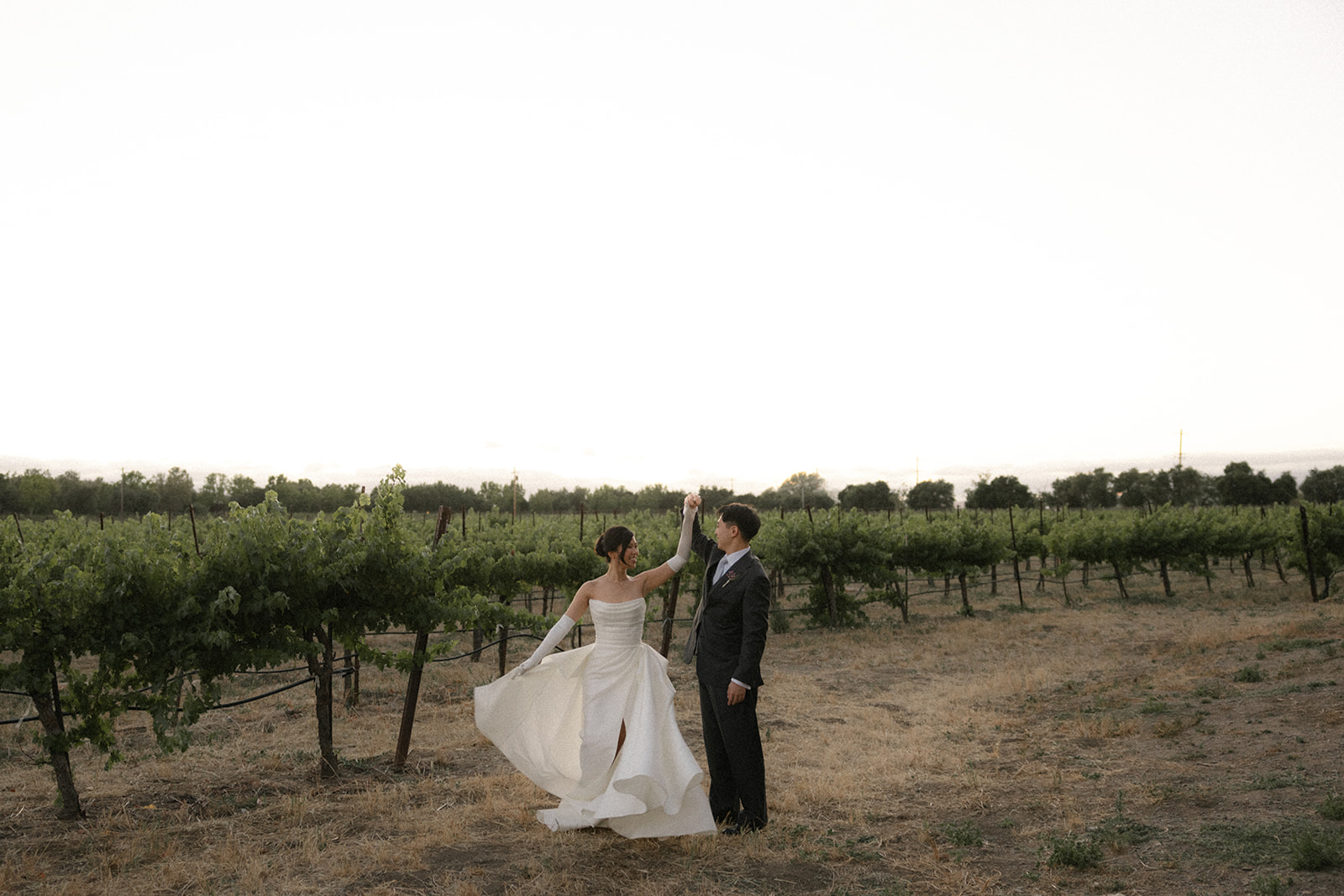Bride and groom dancing together among the vineyard rows at sunset at casa real at ruby hill winery, showcasing one of the most scenic bay area wedding venues.