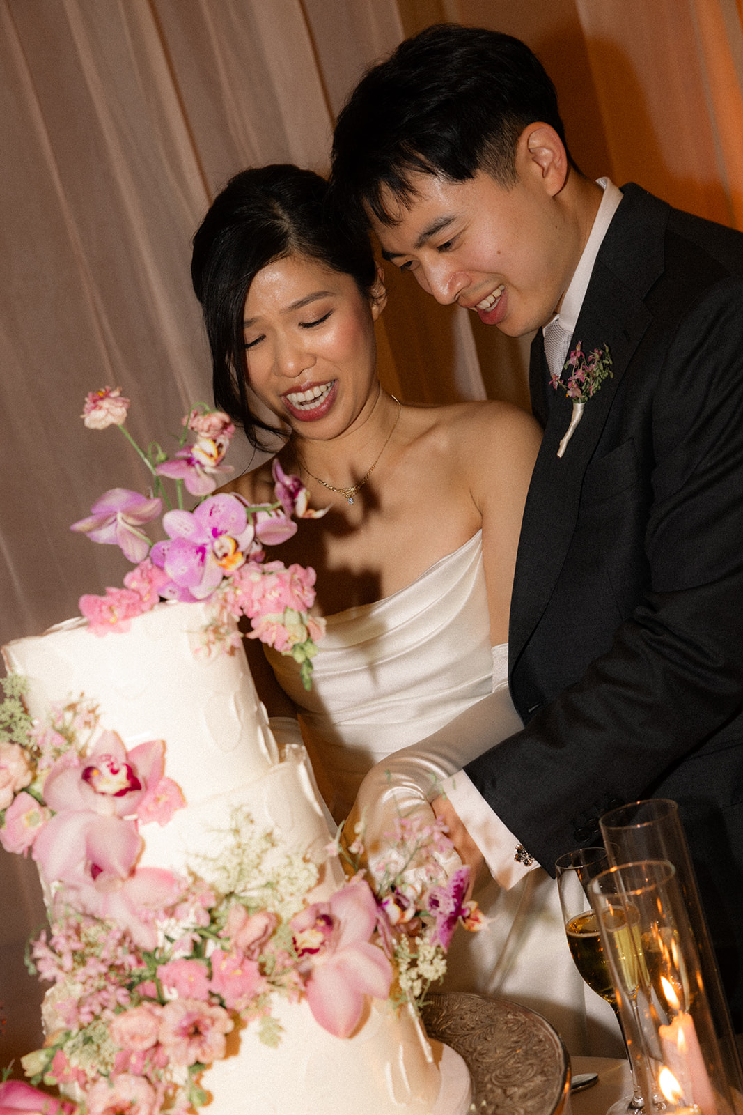 Bride and groom cut their floral wedding cake decorated with pink orchids and blooms during their reception at casa real at ruby hill winery, photographed by a bay area wedding photographer.