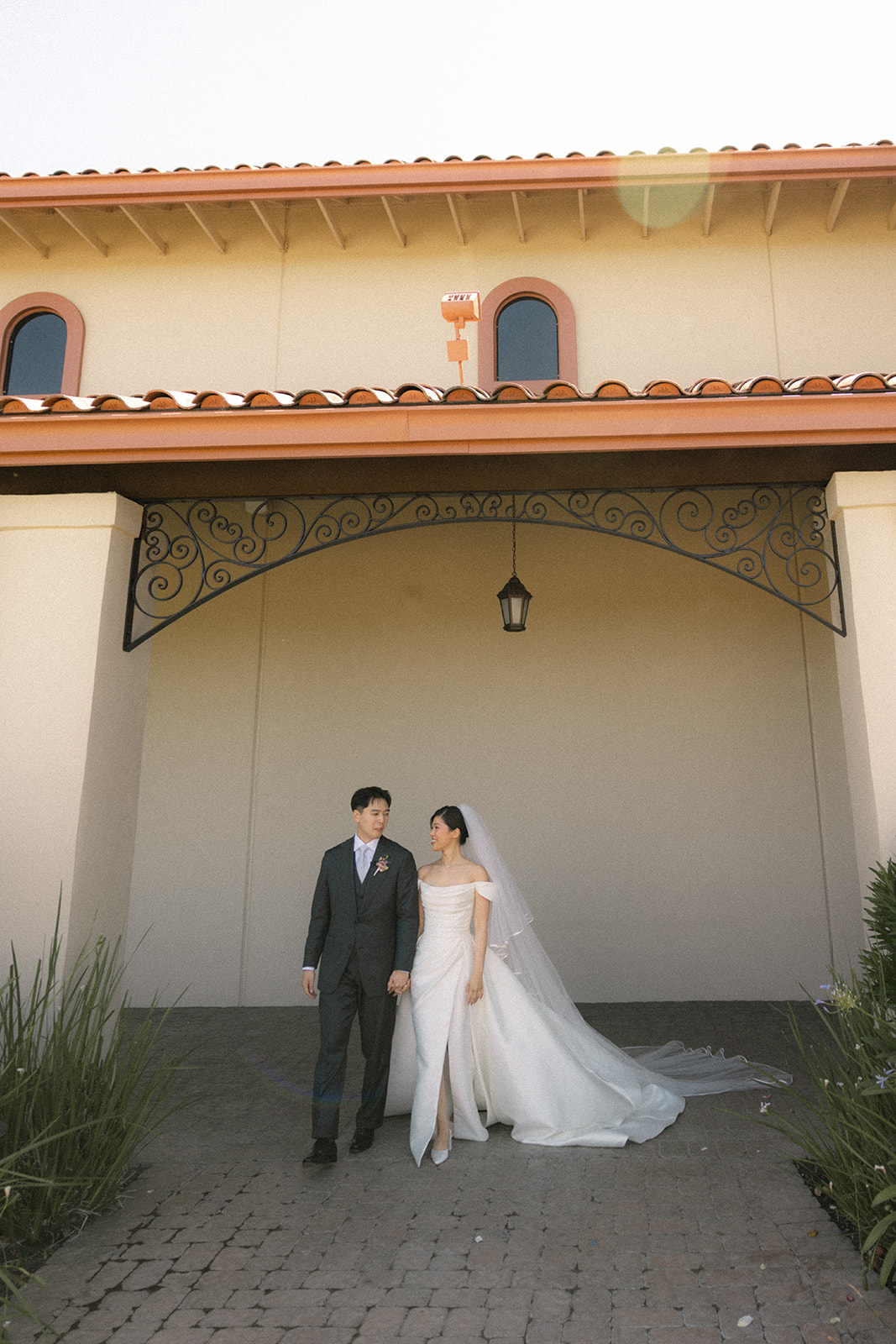 Bride and groom holding hands beneath the archway at casa real at ruby hill winery, showcasing one of the most elegant bay area wedding venues
