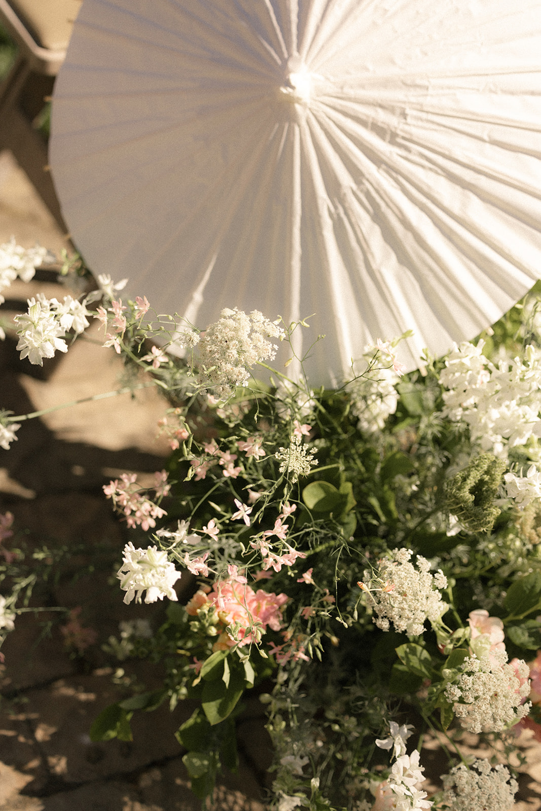 Floral ceremony arrangements with a white paper parasol at casa real at ruby hill winery, photographed by a bay area wedding photographer.