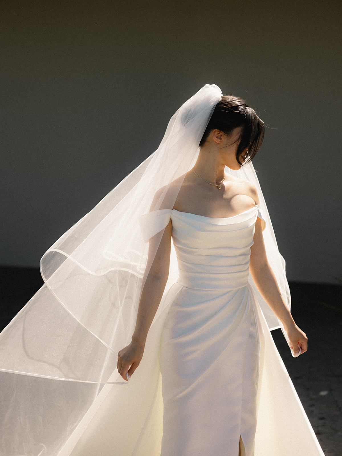 Bride in an off-the-shoulder wedding gown with a flowing veil during bridal portraits at casa real at ruby hill winery