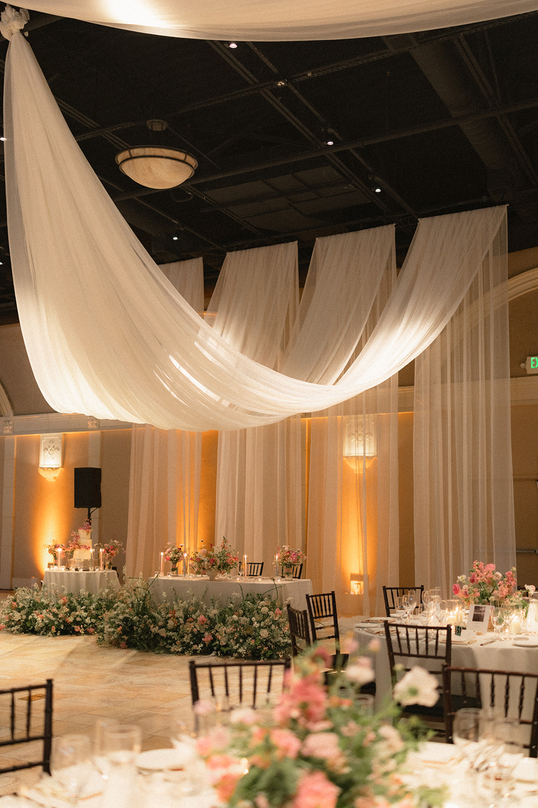 Elegant reception space with flowing ceiling drapery, floral arrangements, and candlelit tables at casa real at ruby hill winery, featured in casa real at ruby hill winery photos.