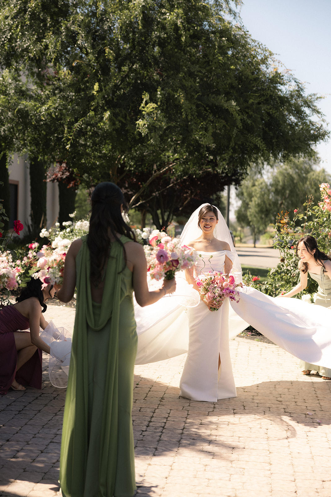 Bride posing with bridesmaids as they arrange her veil and bouquet before portraits at casa real at ruby hill winery, one of the most elegant bay area wedding venues