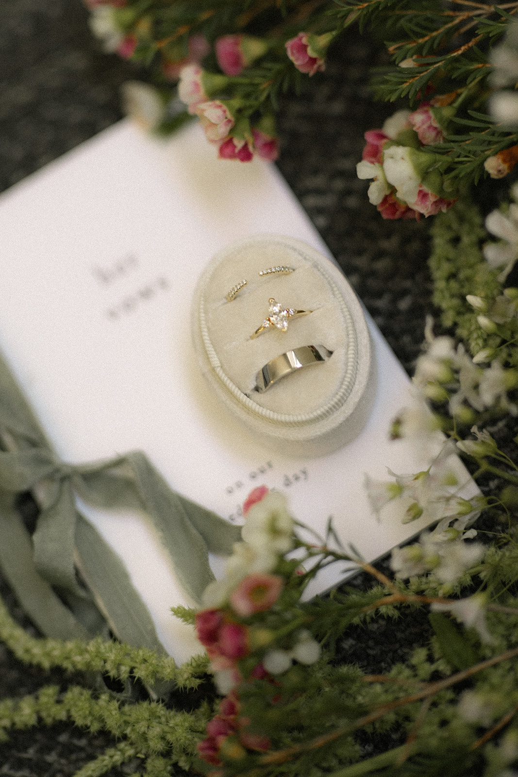 Wedding rings displayed on an invitation suite surrounded by florals at casa real at ruby hill winery, photographed by a bay area wedding photographer
