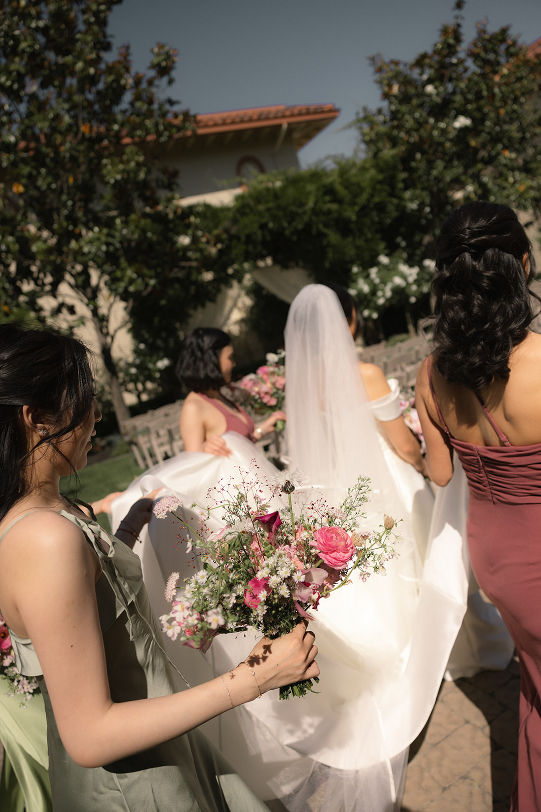 Bridesmaids helping the bride carry her gown and bouquet before the ceremony at casa real at ruby hill winery, photographed by a bay area wedding photographer.