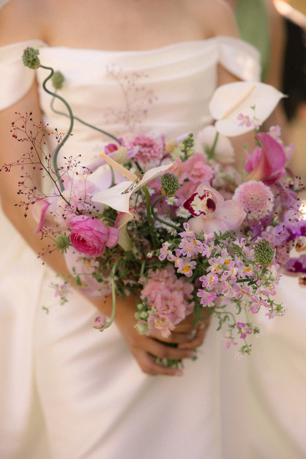 Close-up of the bride holding a lush pink and white floral bouquet with orchids, calla lilies, and ranunculus at casa real at ruby hill winery, photographed by a bay area wedding photographer.