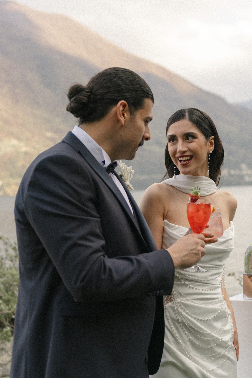 Bride and groom enjoying signature cocktails together by the lake, photographed by a destination wedding photographer.