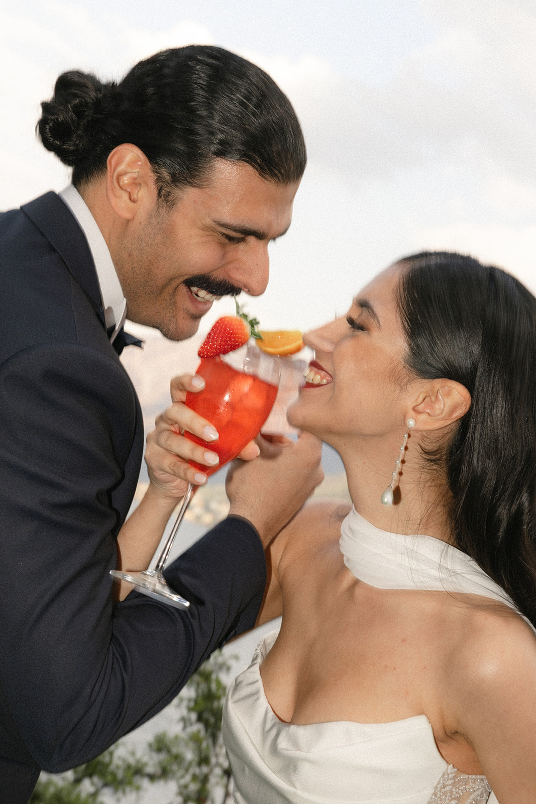 Bride and groom sharing a playful toast with signature cocktails, photographed by a destination wedding photographer.