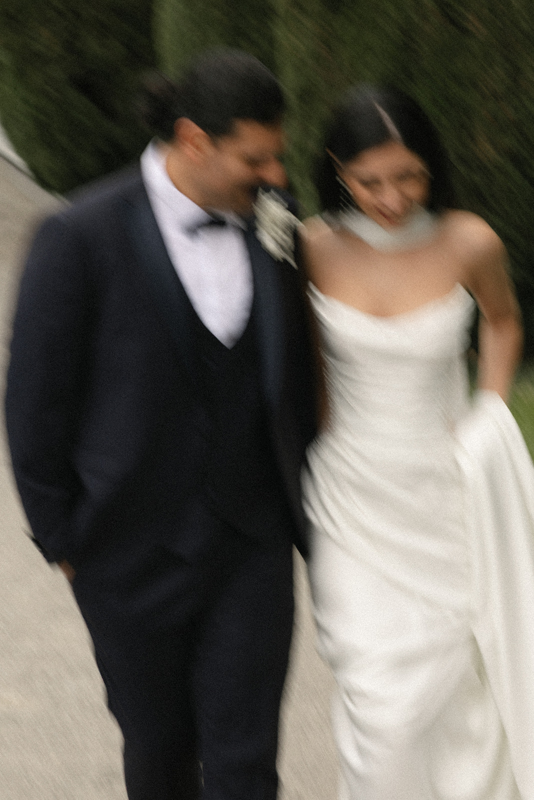 Bride and groom walking together in the garden, captured with intentional motion blur for a candid destination wedding portrait.