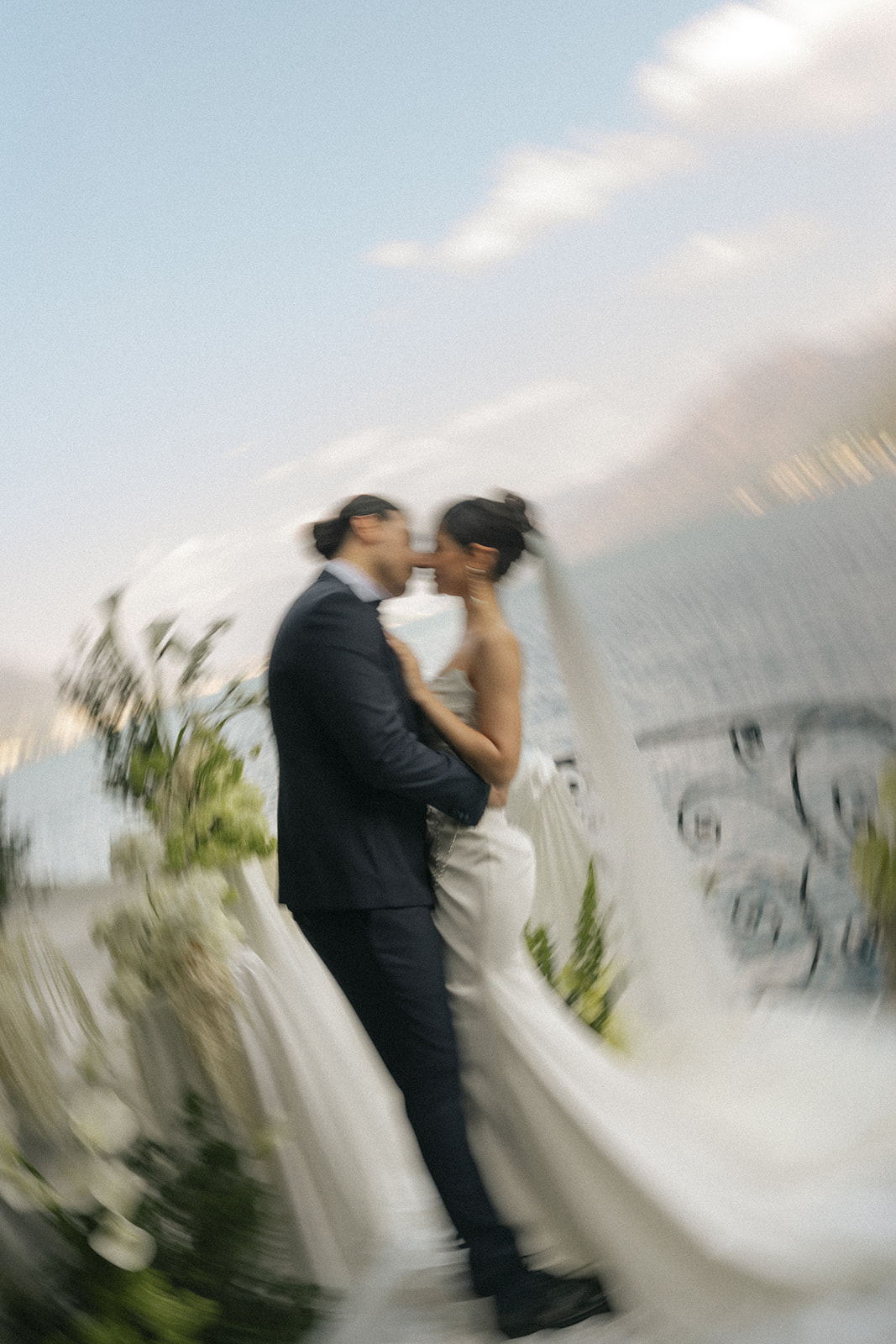 Bride and groom sharing a kiss on a lakeside terrace, captured with creative motion blur during a Lake Como wedding.