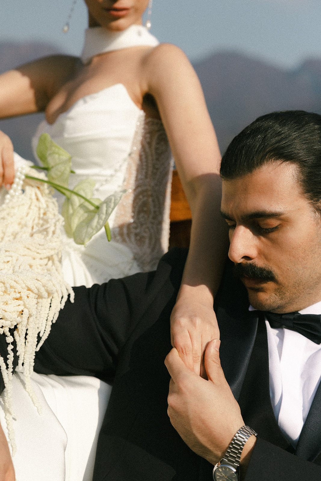 Close-up of the groom gently holding the bride's hand aboard a wooden boat, photographed by a destination wedding photographer.