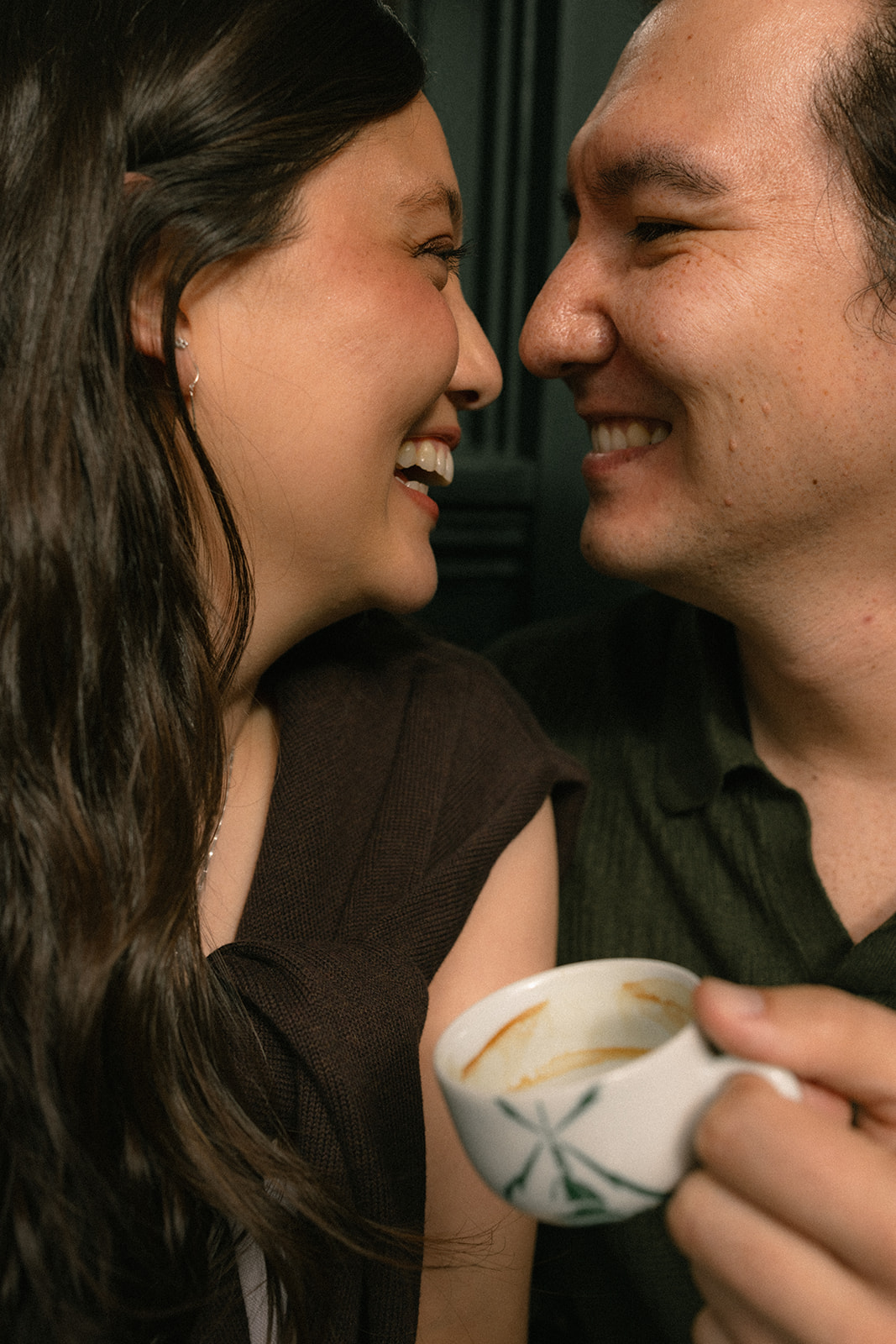 Close-up of a couple smiling nose-to-nose while sharing a coffee, capturing an intimate candid moment.