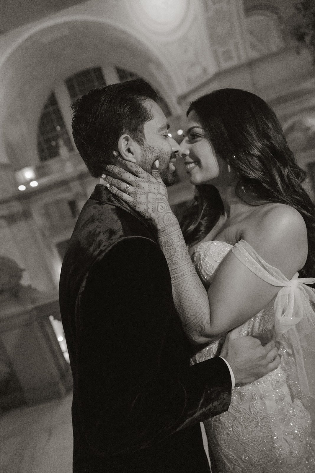 Black-and-white San Francisco City Hall wedding photos of the newlyweds embracing beneath the rotunda, highlighting the bride’s intricate henna and off-the-shoulder gown.