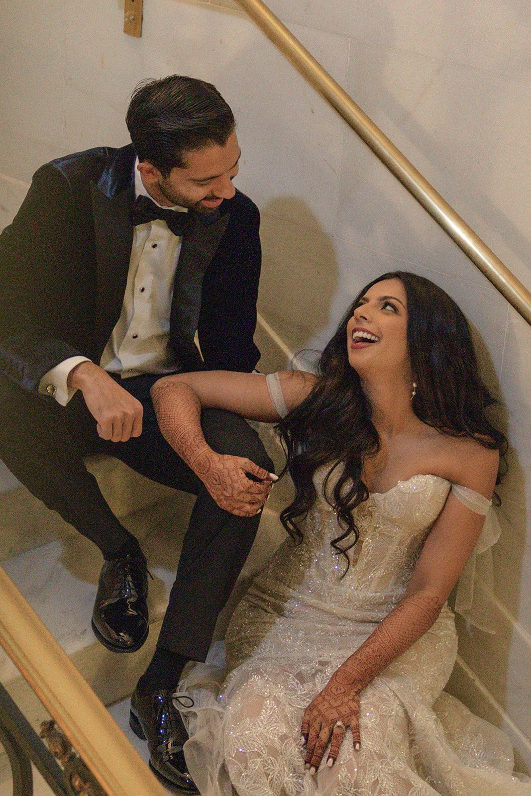 Bride and groom share a candid moment on the City Hall staircase, captured by a San Francisco City Hall photographer after their ceremony.
