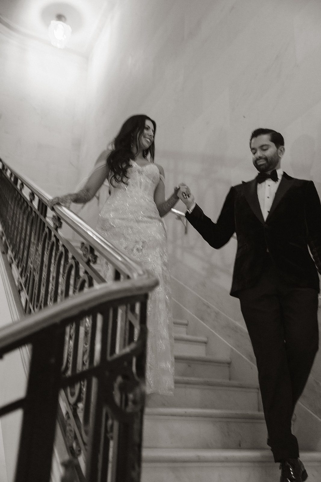 Couple walking hand in hand down a marble staircase during their San Francisco City Hall wedding.