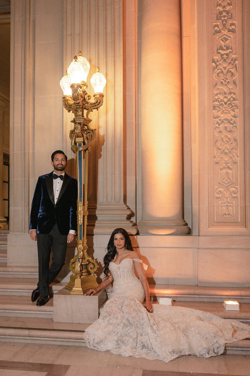 Couple posing beside an ornate lamp and grand columns during their San Francisco City Hall wedding portraits.