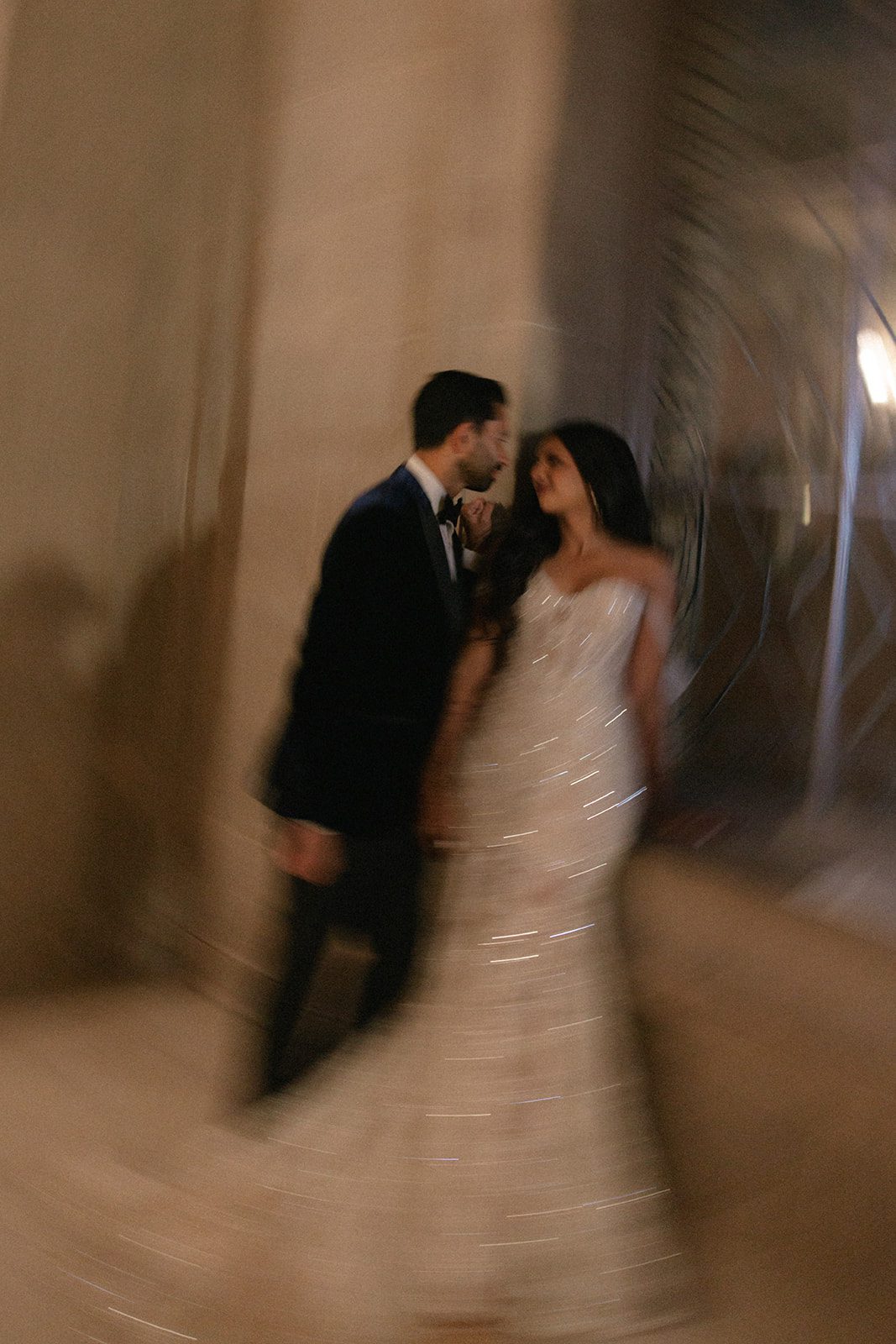 Artistic motion-blur portrait from a San Francisco City Hall wedding, showing the couple together in an ornate hallway with the bride’s beaded gown catching the light.