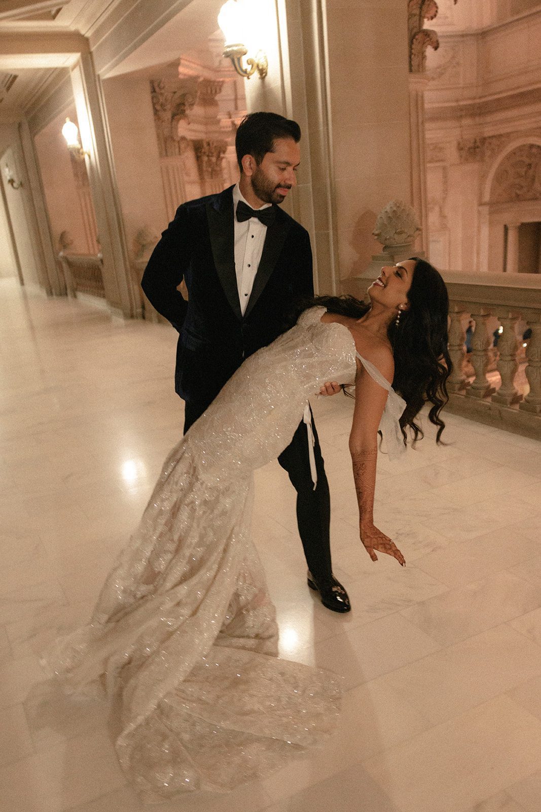 Groom dips the bride during their San Francisco City Hall wedding, surrounded by marble floors and ornate interior architecture.