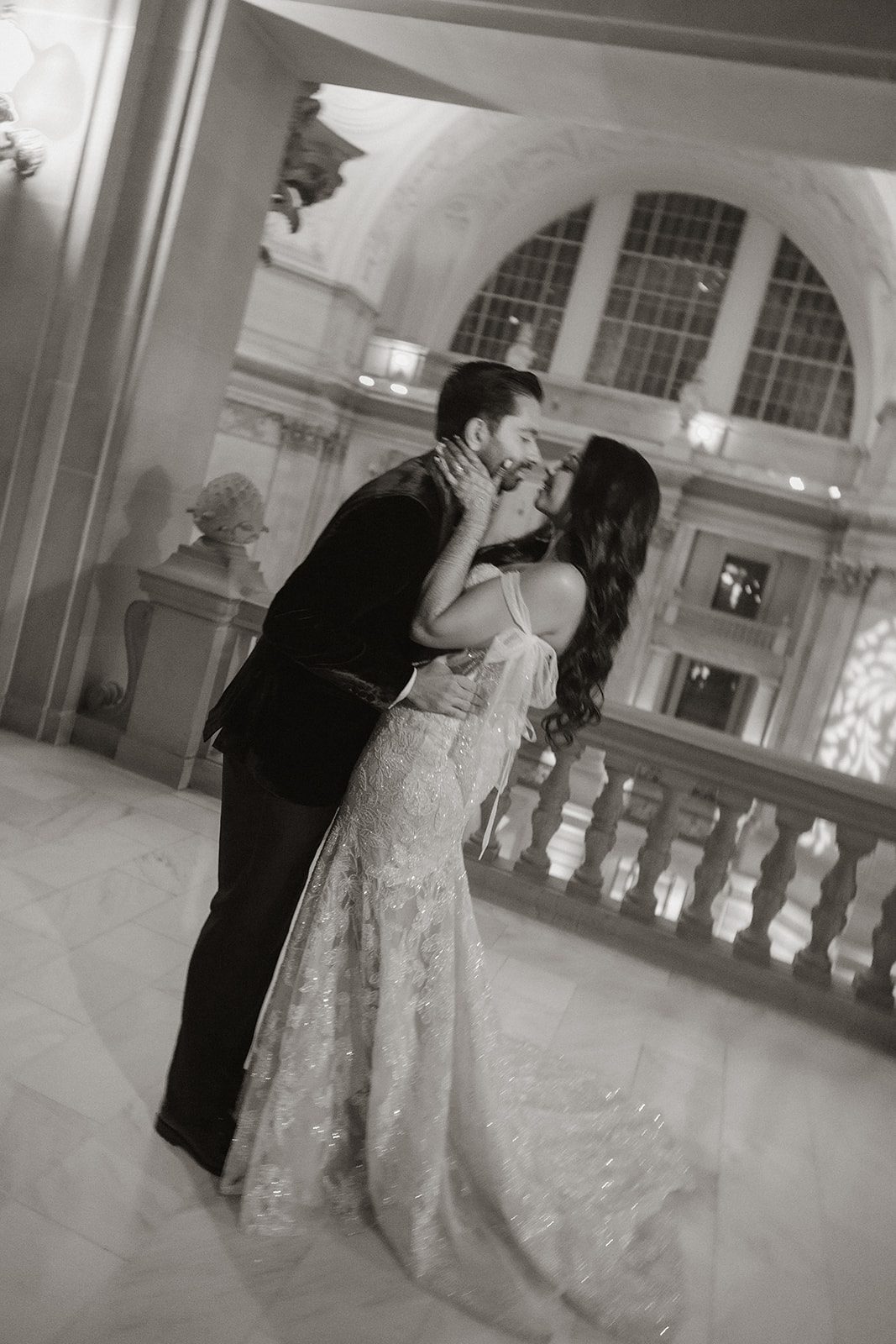 Black-and-white San Francisco City Hall wedding portrait of the newlyweds embracing beneath the grand arches, with the bride’s beaded gown and henna details visible.