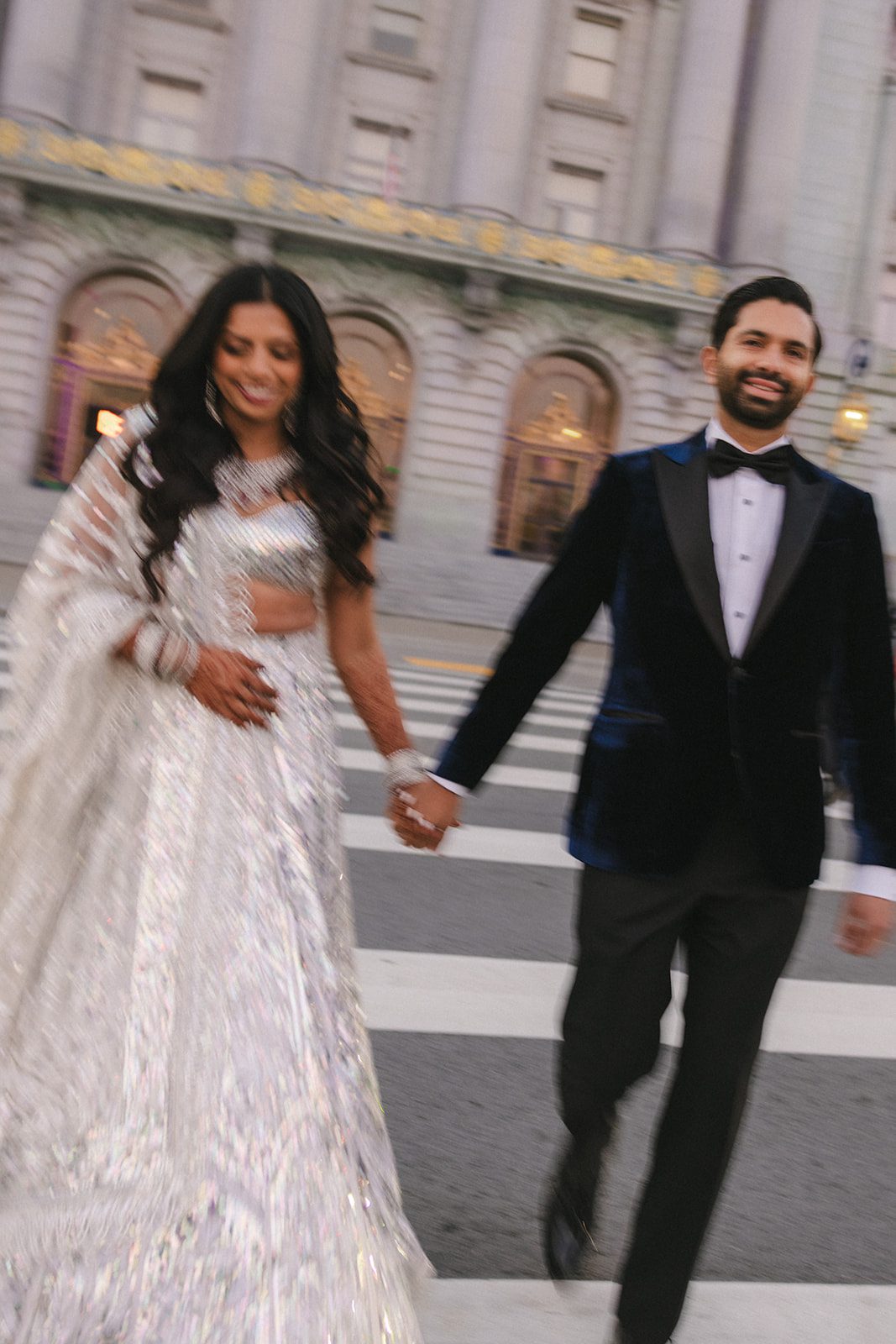 Newlyweds walk hand in hand outside City Hall after their San Francisco City Hall wedding, captured in a motion-blurred street portrait by a Bay area wedding photographer.