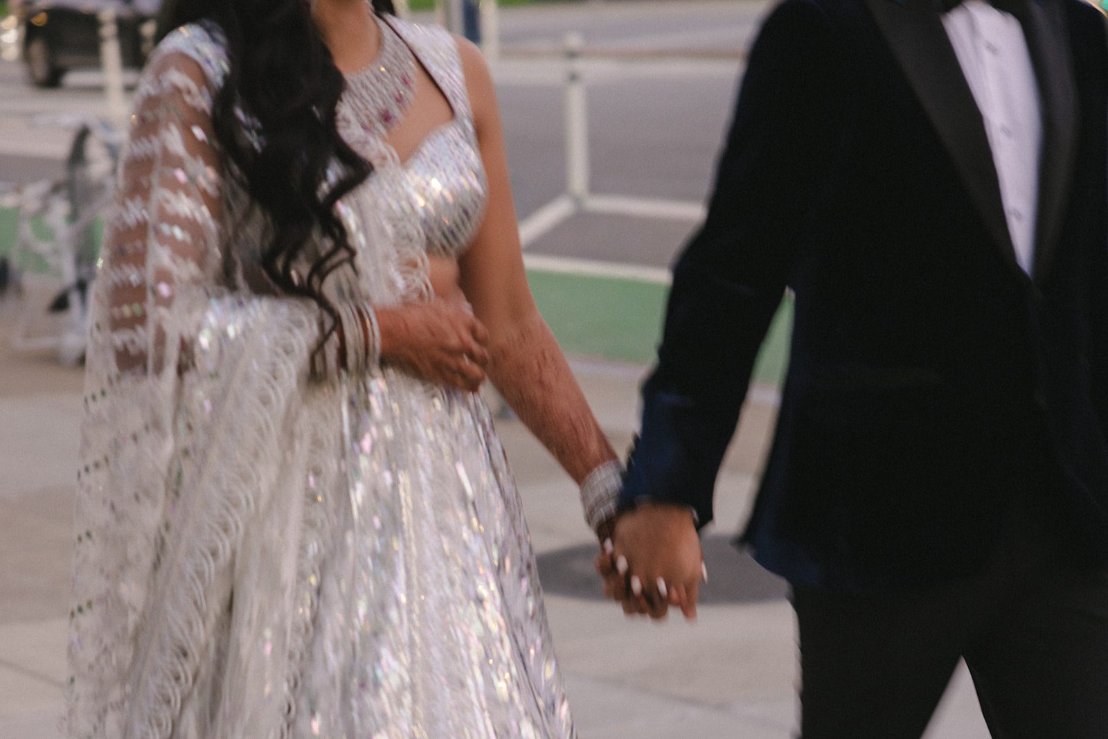 Close-up of a couple holding hands while walking outdoors after their San Francisco City Hall wedding.