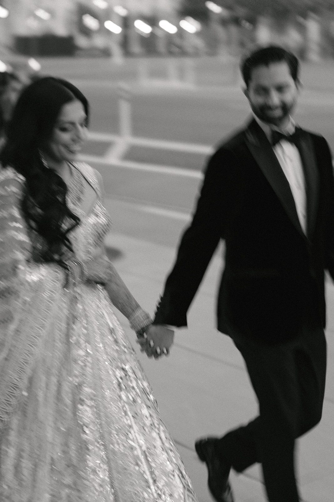 Black-and-white candid of a couple holding hands and walking together after their San Francisco City Hall wedding.