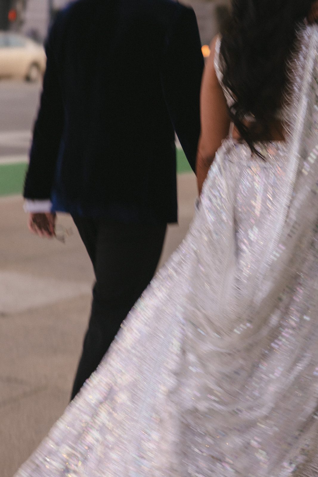 Detail photo of the bride’s sparkling lehenga flowing as the couple walks away from their San Francisco City Hall wedding portrait session.