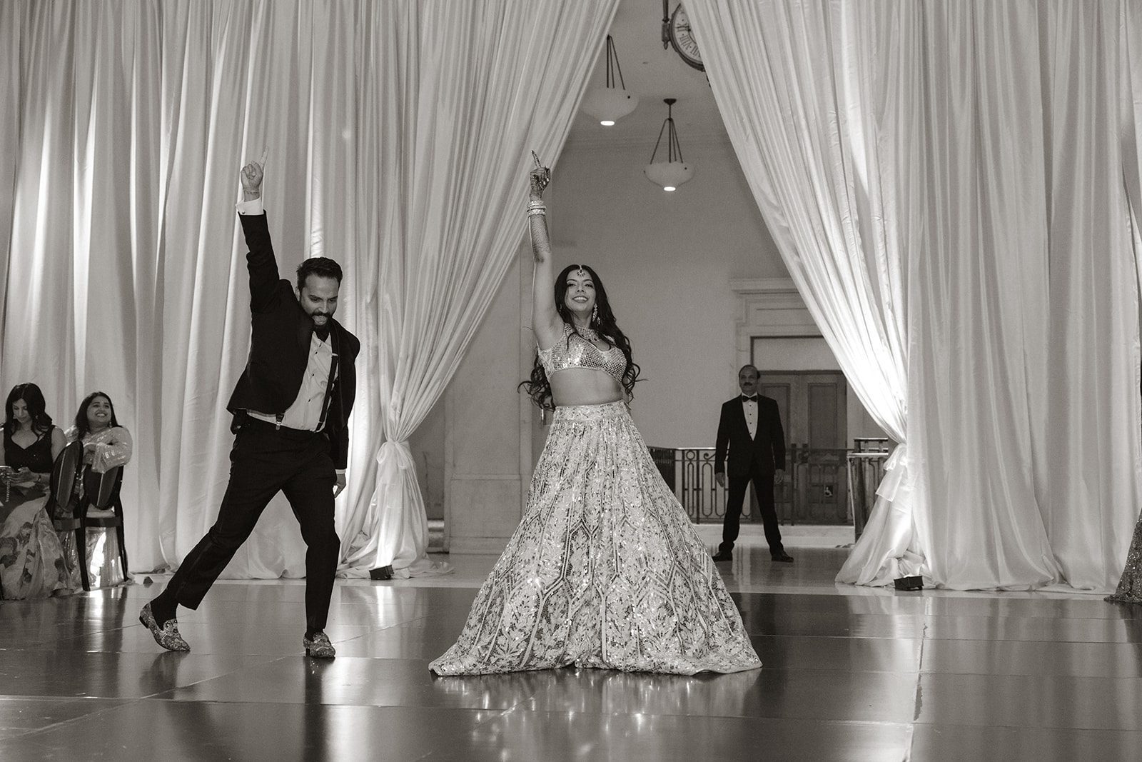 Black-and-white San Francisco City Hall wedding reception photo of the bride and groom performing a coordinated dance beneath elegant floor-to-ceiling draping.