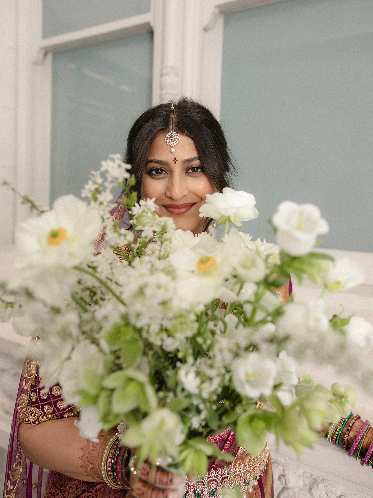 Bridal portrait framed by soft white flowers during an Indian wedding at the Conservatory at One Sansome.