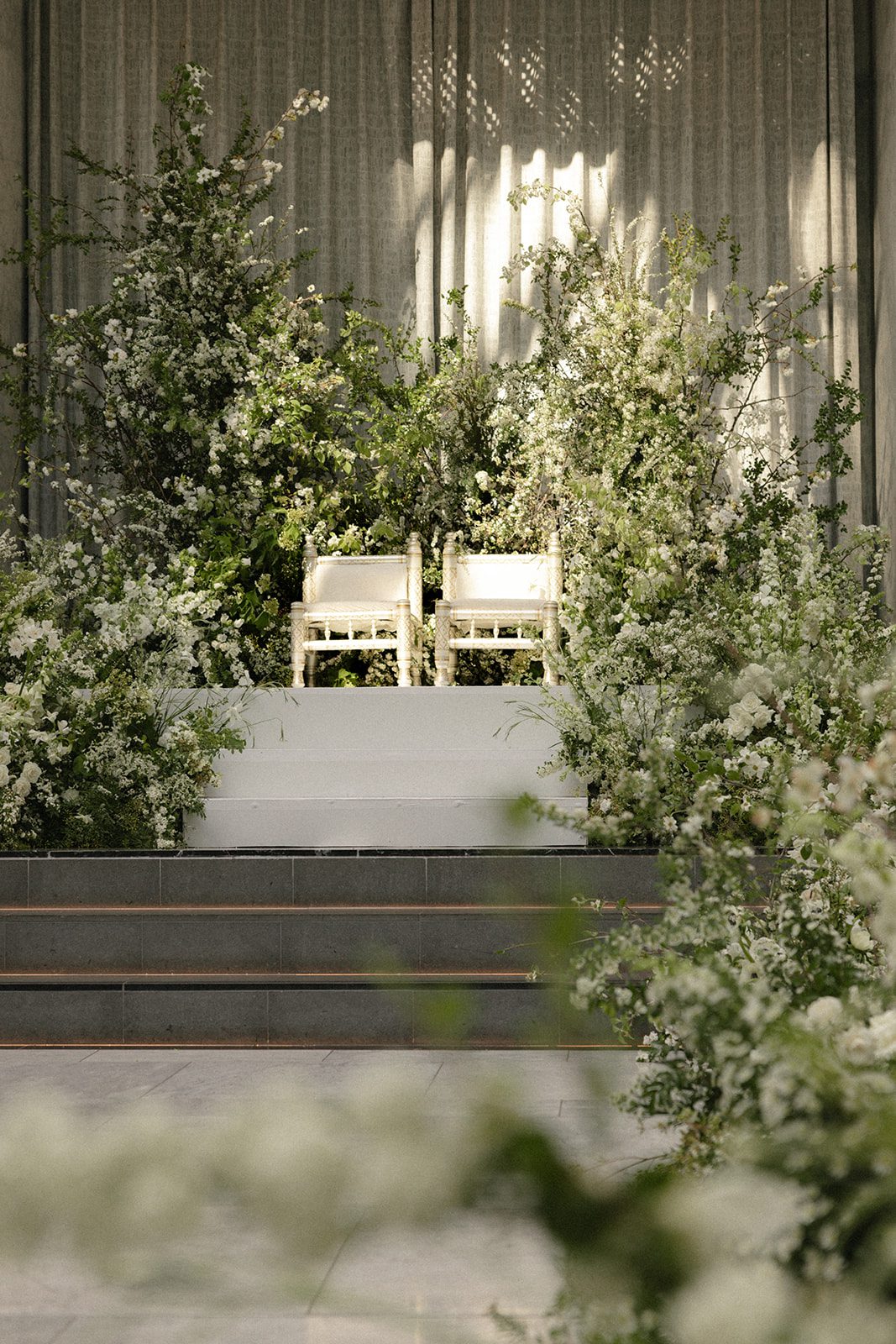 Lush white flowers and greenery frame the ceremony seating for The Conservatory at One Sansome wedding.