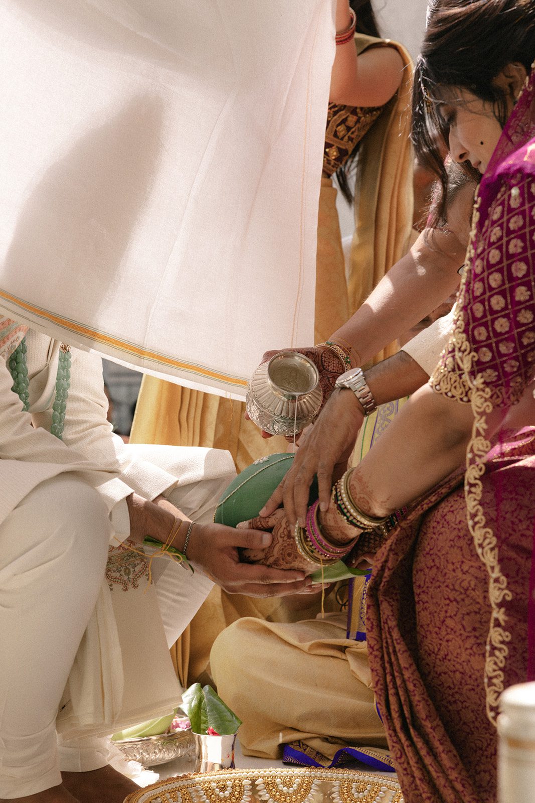 Close-up of a traditional Telugu wedding ritual as family members pour water over the bride’s feet during the ceremony.