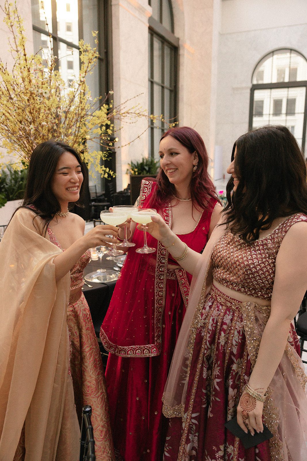 Wedding guests in colorful Indian attire toast with cocktails during the reception at the Conservatory at One Sansome.