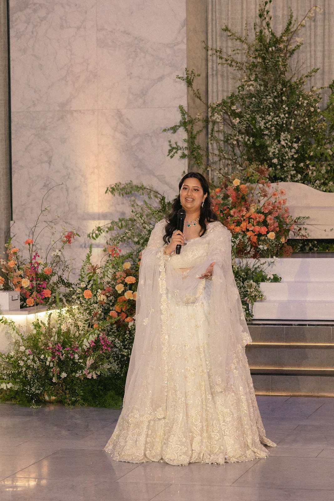 Wedding guest gives a reception speech surrounded by colorful floral installations at The Conservatory at One Sansome wedding.