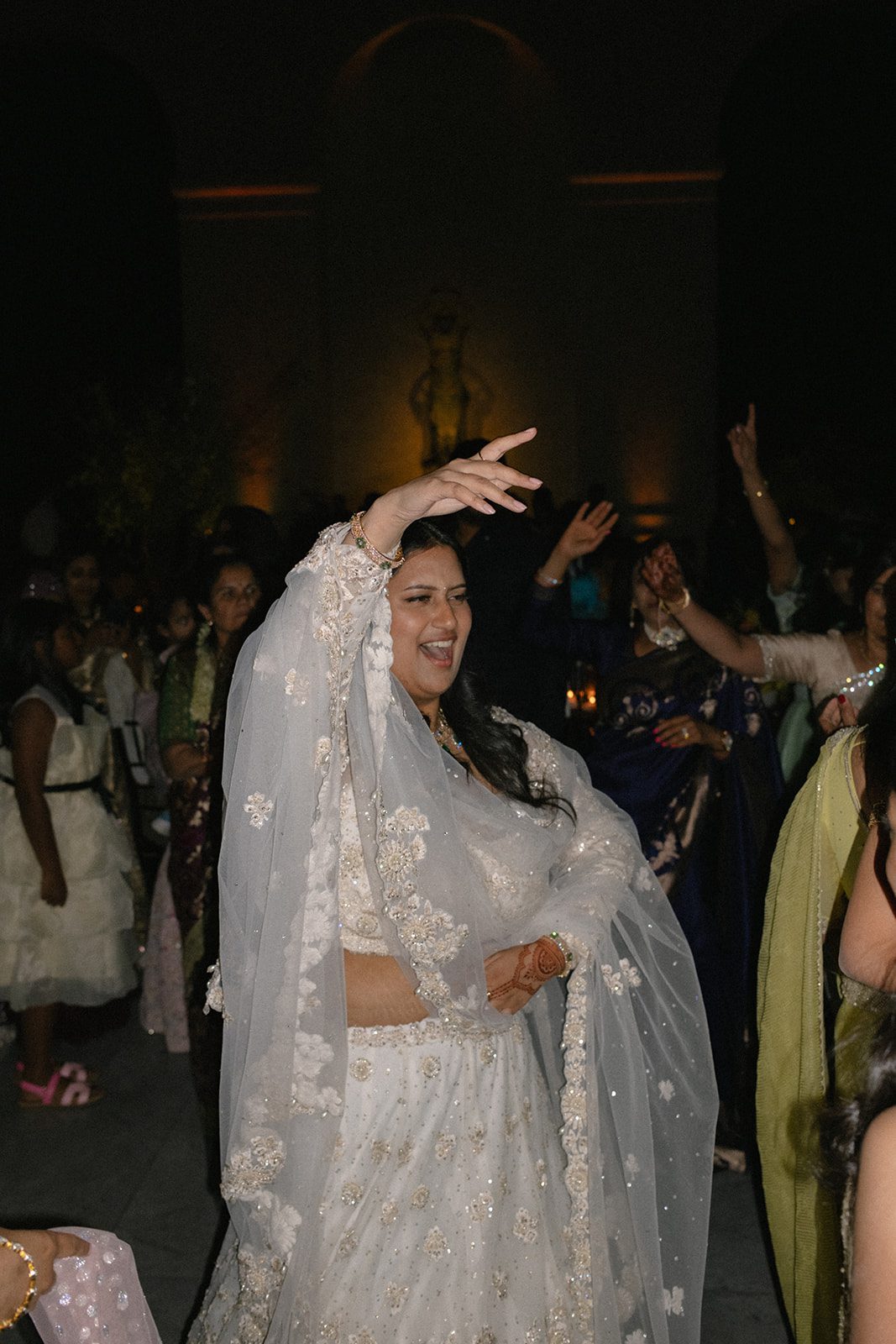 Guest in an embellished white lehenga dances during the evening reception of a multi-day wedding in San Francisco.