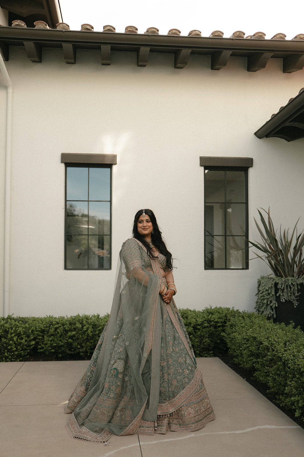 Portrait of the bride in an embroidered sage green lehenga during an Indian wedding celebration.