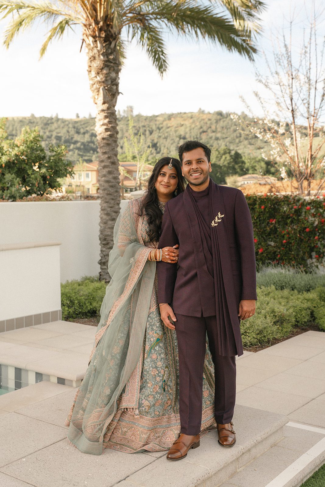 Couple portrait outdoors with the bride in a sage green lehenga and groom in a deep plum suit photographed by San Francisco wedding photographer