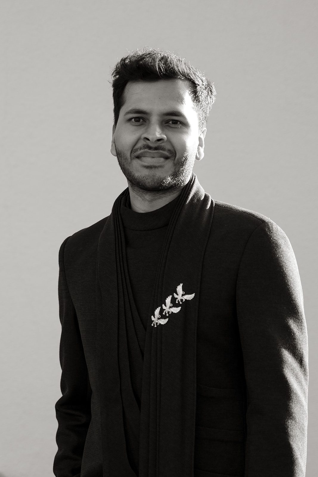 Black-and-white portrait of the groom in a modern embroidered suit during the Indian wedding celebration.